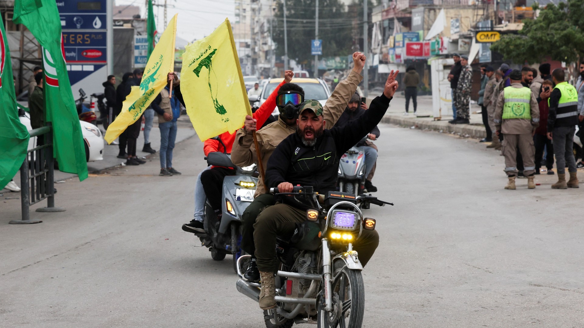 A man gestures as he holds a Hezbollah flag in Tyre, after a ceasefire between Israel and Lebanon took effect on 27 November 2024 (Aziz Taher/Reuters)