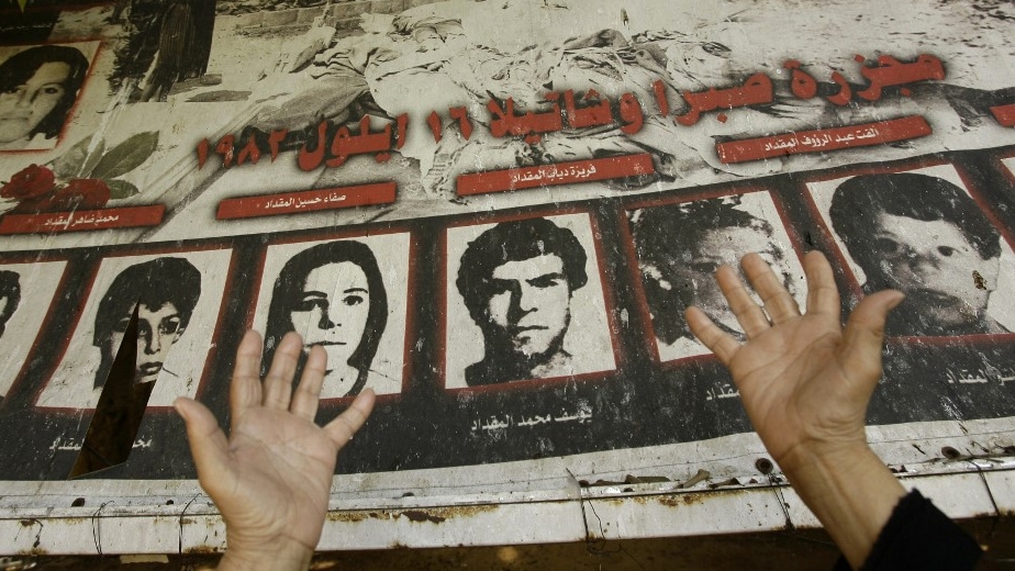 A Palestinian woman prays by a poster bearing pictures of her slain relatives at a memorial on the anniversary of the Sabra and Shatila massacre in Beirut in September 2010 (Anwar Amro/AFP)