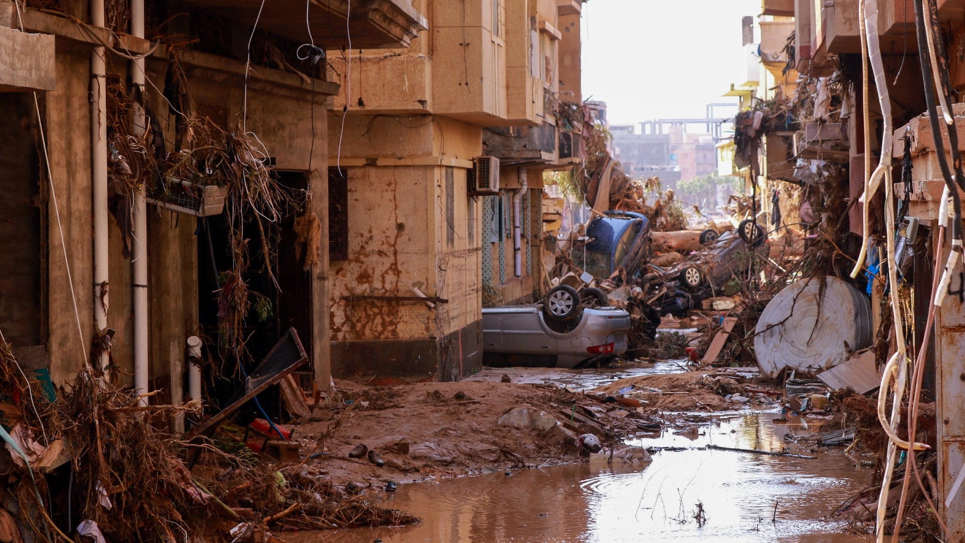 Overturned cars lay among other debris caused by flash floods in Derna, eastern Libya, on 11 September 2023 (AFP)