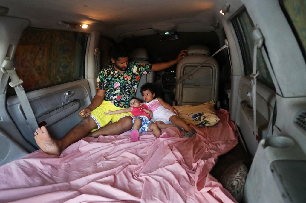 Mahmoud Aguil dort en famille dans sa voiture pour profiter de la climatisation (AFP/Mahmud Turkia)