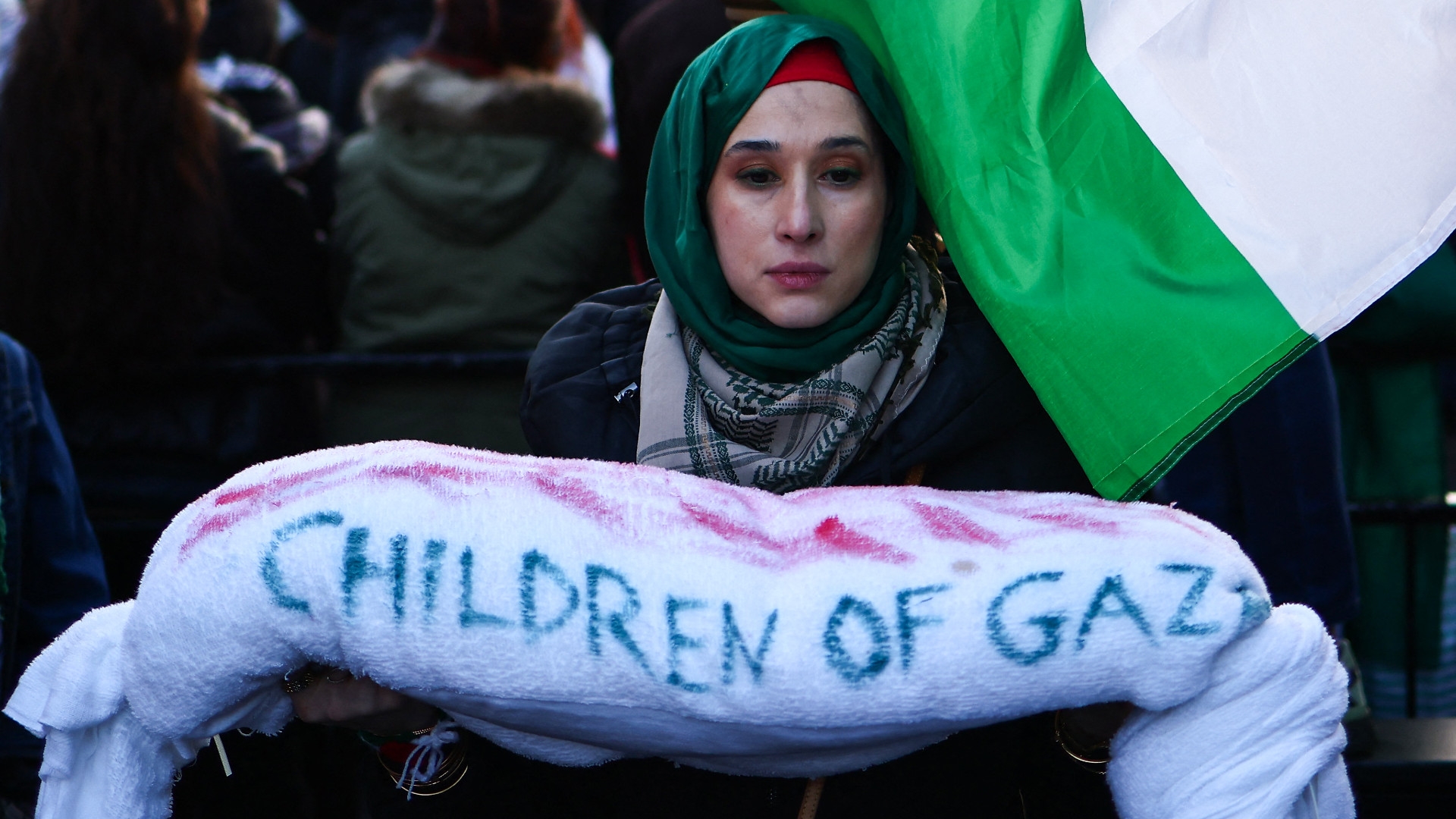 A protester holds a symbolic shrouded, deceased Palestinian child while attending a march calling for a ceasefire in Gaza, in central London on 9 December 2023 (Henry Nicholls/AFP)