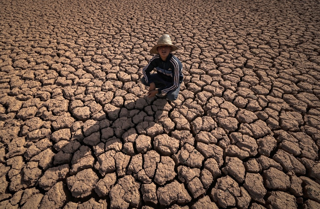 Un enfant s’accroupit sur la terre fissurée du barrage d’al-Massira dans le village d’Ouled Essi Masseoud, au sud de Casablanca, le 8 août 2022 : le Maroc connaît sa pire sécheresse depuis au moins quatre décennies (AFP/Fadel Senna)