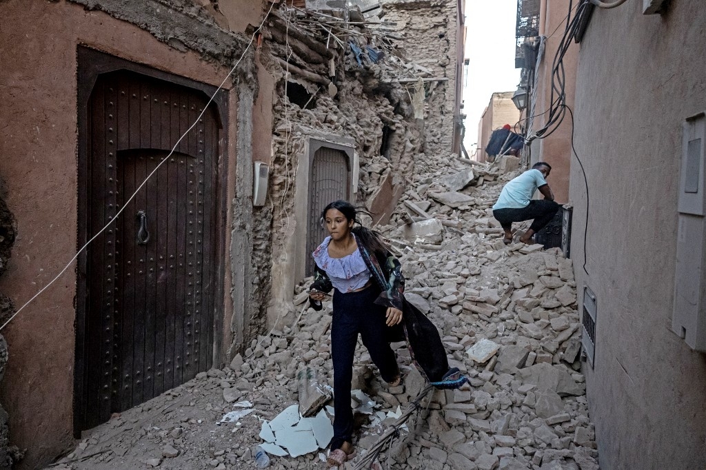 Une femme évacue sa maison avec ses affaires à travers les décombres dans la vieille ville de Marrakech, le 9 septembre 2023 (AFP/Fadel Senna)