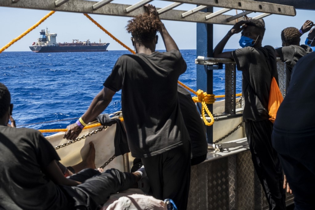 Migrants onboard a civil sea rescue ship watch towards the oil tanker Maersk Etienne off the coast of Malta on 27 August 2020.