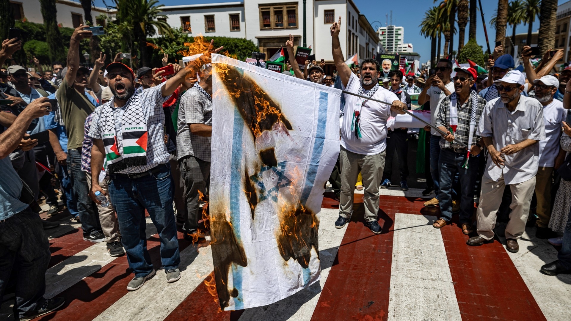 Demonstrators burn the Israeli flag during a rally in Rabat on 3 August, protesting against the killing of Hamas leader Ismail Haniyeh (Fadel Senna/AFP)