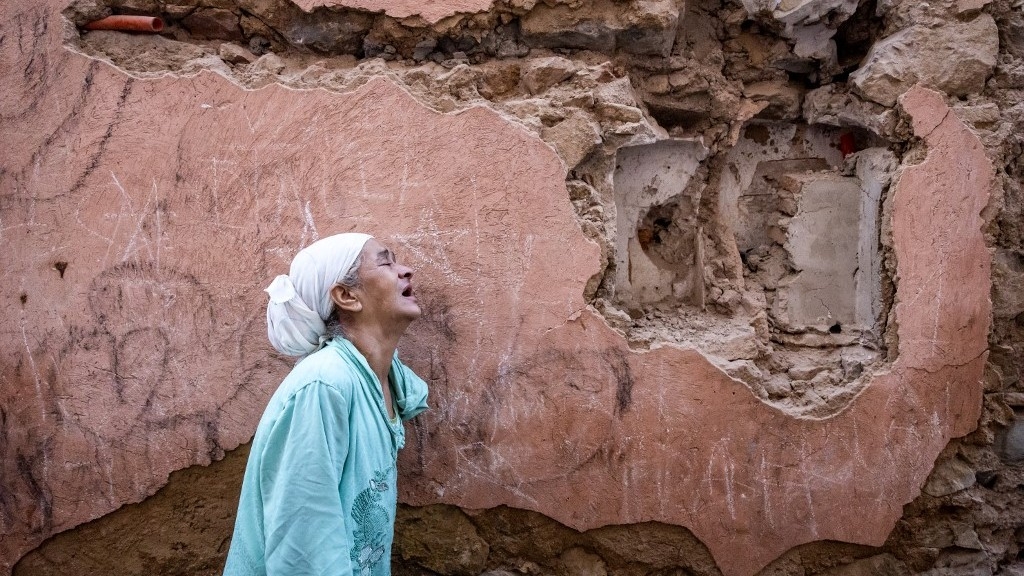 A woman reacts standing in front of her earthquake-damaged house in the old city in Marrakesh on 9 September 2023 (AFP)