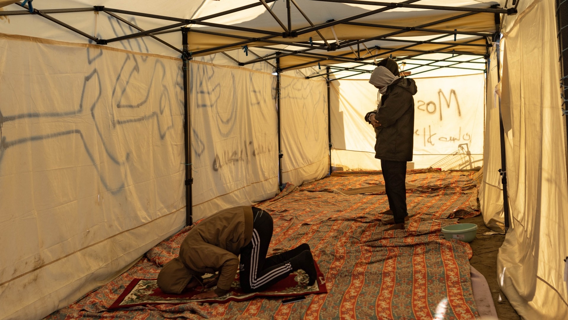 A group of men pray inside the makeshift mosque built in the camp of Grande Synthe, in the forest of Dunkirk, France (MEE/Marta Maroto)