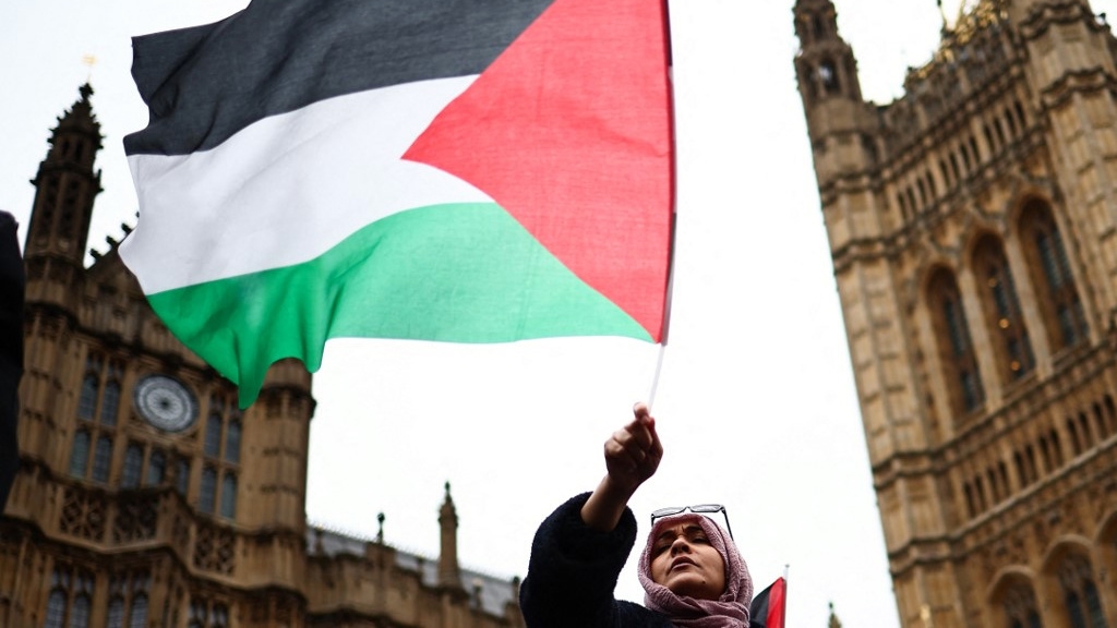 A demonstrator waves a Palestinian flag during a protest in London on 21 February 2024 (Henry Nicholls/AFP)