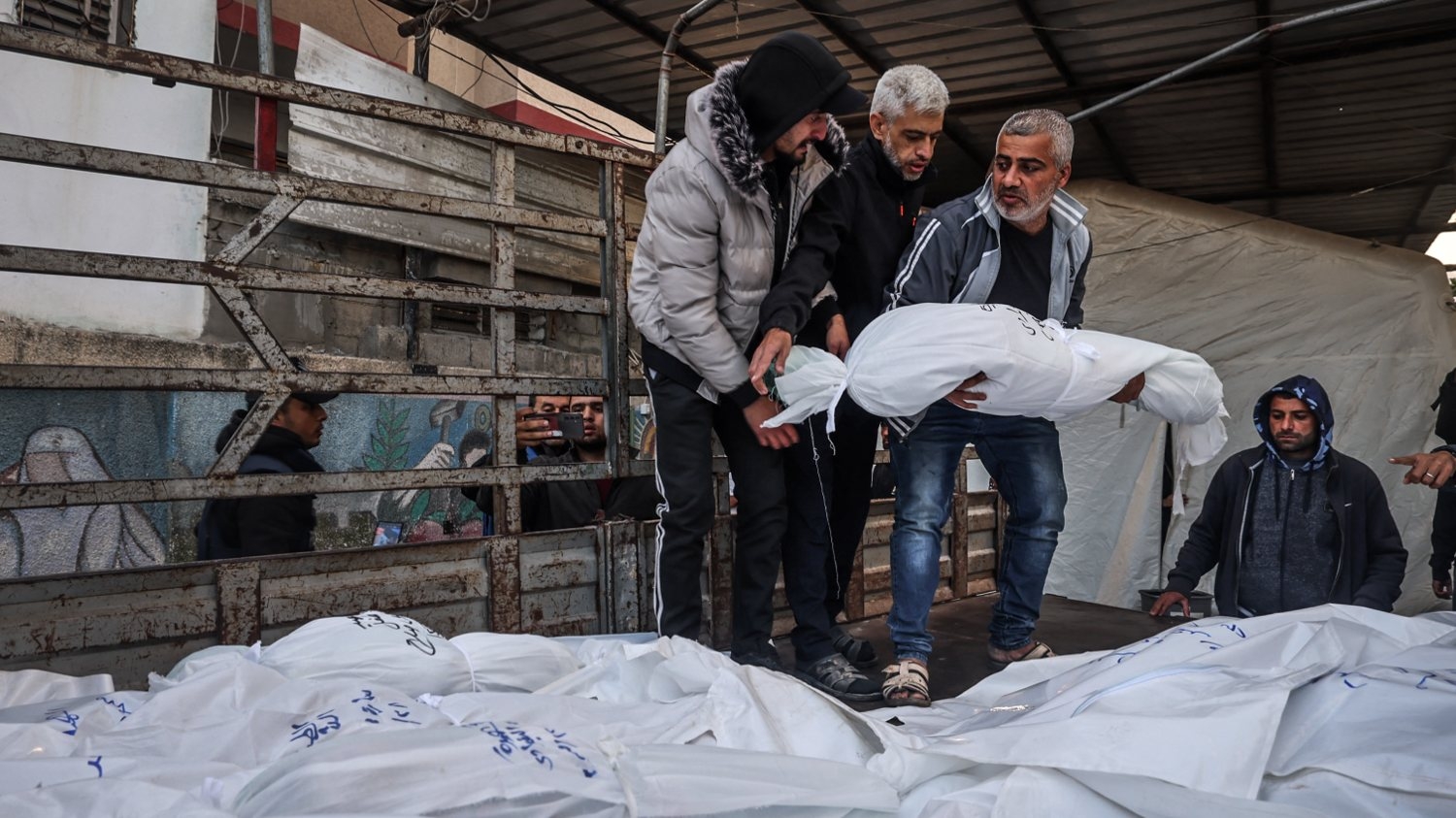 The shrouded bodies of people killed in Rafah during Israeli bombardment on the southern Gaza strip, are placed on a truck for burial outside Al-Najar hospital on 29 December 2023.