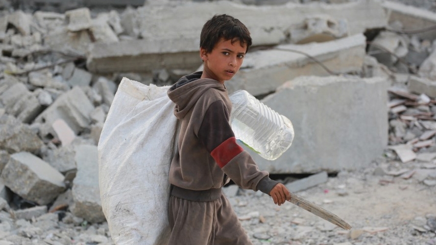 A Palestinian boy salvages items from rubble in Khan Younis, Gaza, on 22 July 2024 (Bashar Taleb/AFP)