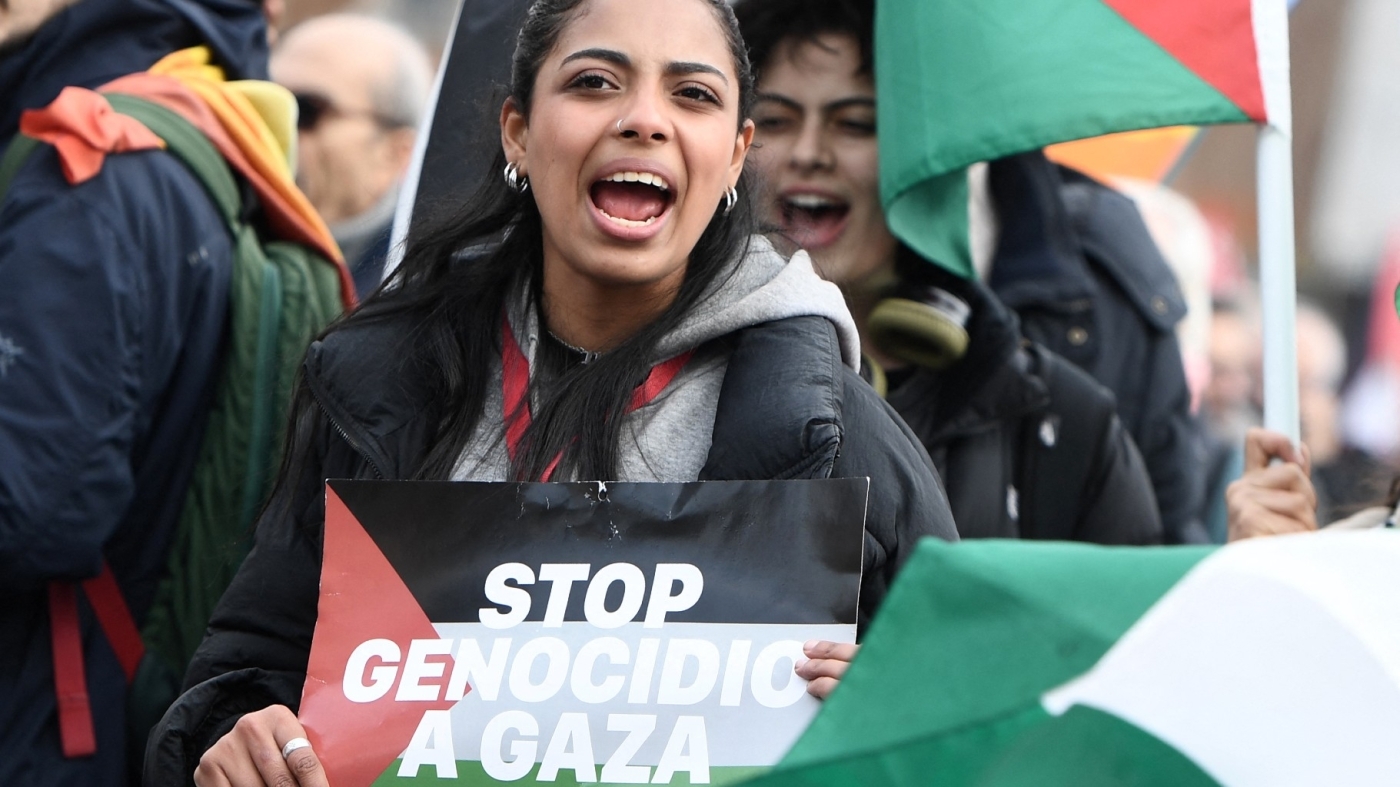 A demonstrator holds a placard reading "Stop genocide in Gaza" during a national peace demonstration in Rome on 9 March, 2024 (AFP)
