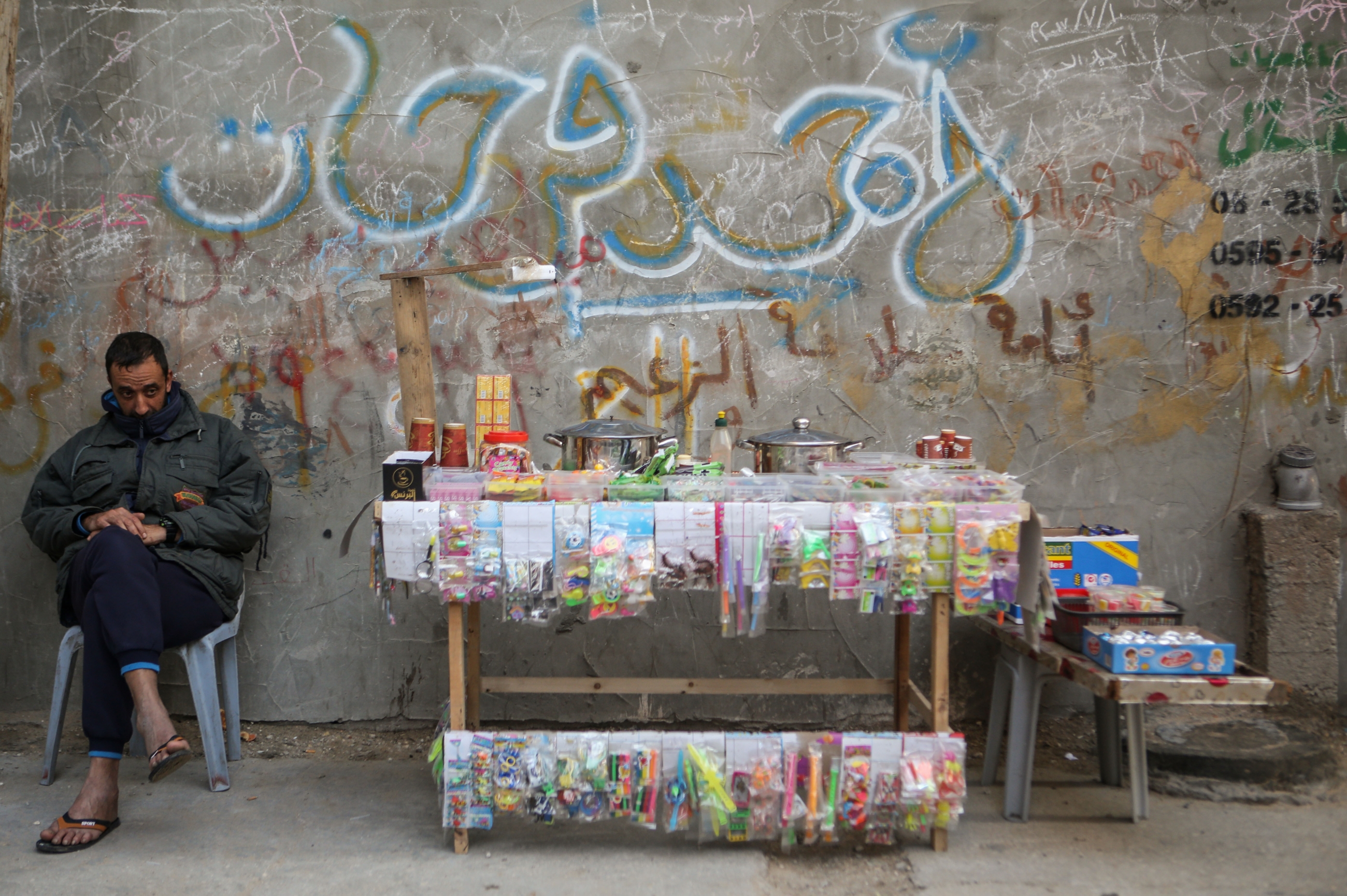 A Palestinian vendor sits by his sweets and children toys cart in al-Shati refugee camp west of Gaza on 2 January 2018 (MEE/Mohammed al-Hajjar)