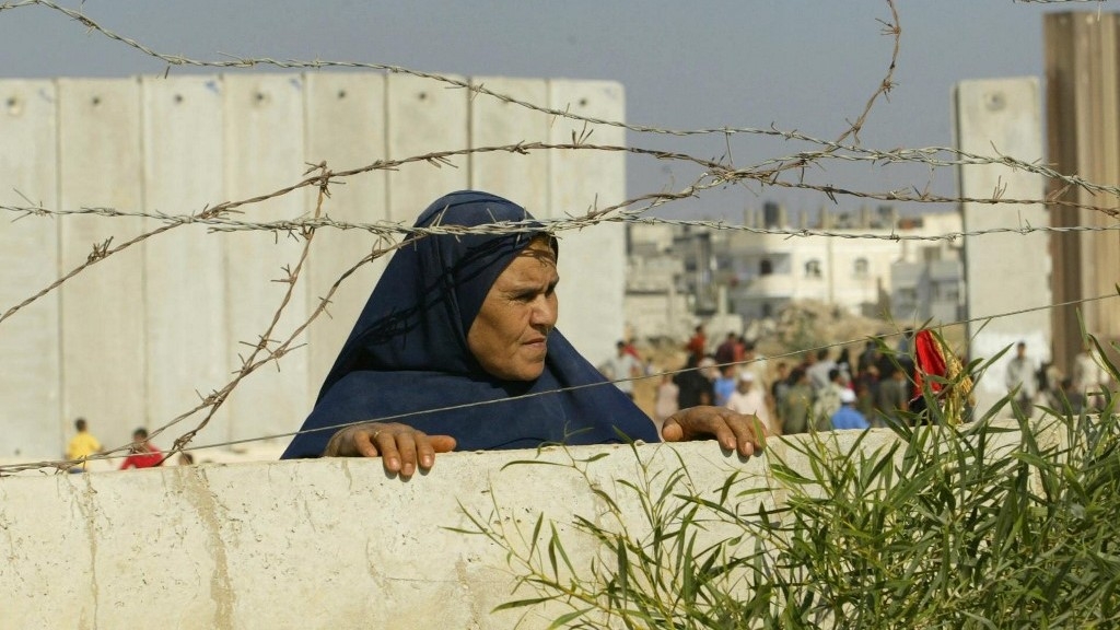 A Palestinian woman stands while looking into Egypt along the Gaza-Egypt boundary on 12 September 2005 (AFP)