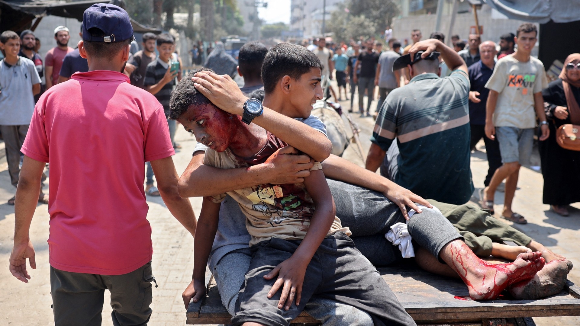 Palestinians injured during an Israeli strike on the Khadija school housing displaced people, ride on the back of a cart in Deir al-Balah, in the central Gaza Strip on 27 July, 2024 (Eyad Baba/AFP)