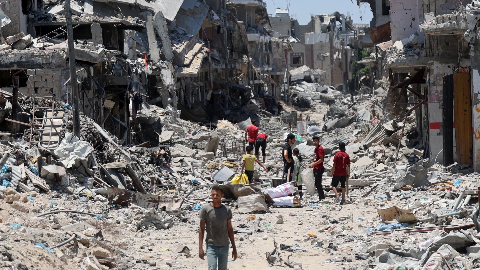 Palestinians make their way over the rubble of past destroyed buildings in the Shujaiya neighbourhood, east of Gaza City, on 11 July, 2024 (Omar al-Qattaa/AFP)