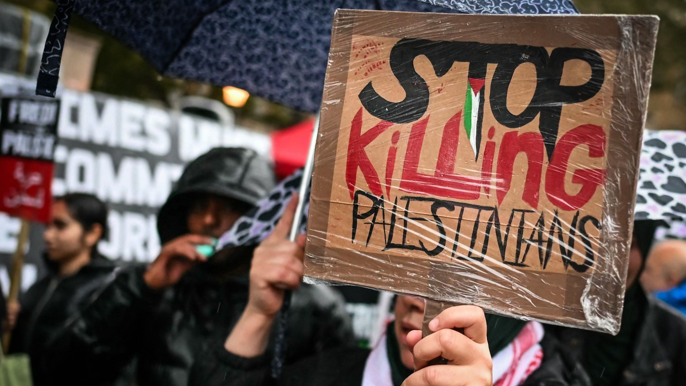 A protester holds a banner during a vigil in support of Palestinians in Gaza outside Downing Street on 18 October (Justin Tallis/AFP)