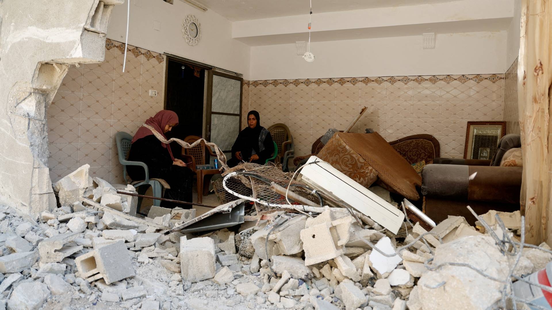 Women sit inside a damaged building in the Nur Shams refugee camp in the aftermath of an Israeli raid on 23 July 2024 (Raneen Sawafta/Reuters)