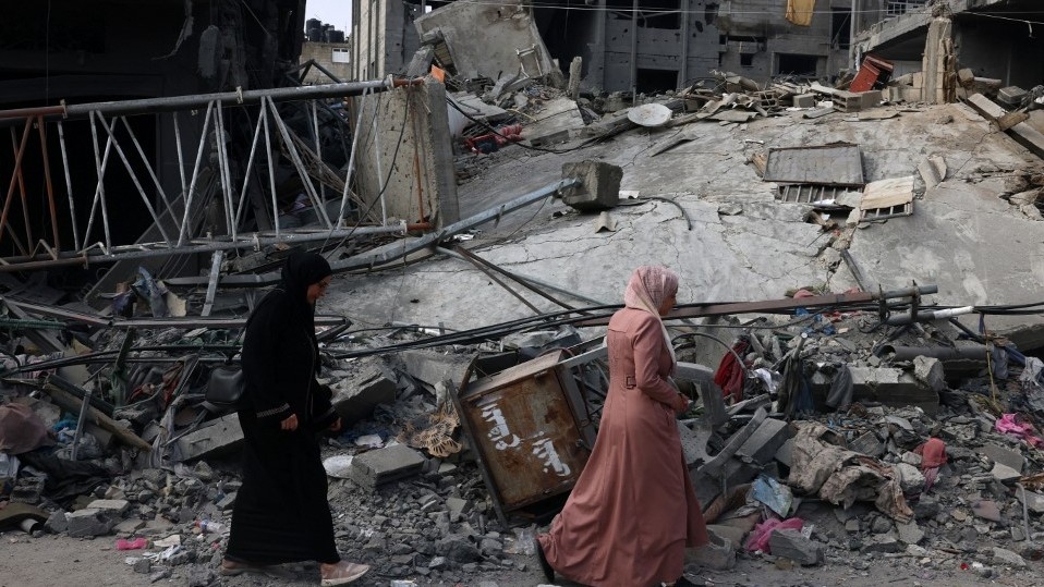 Des femmes longent un bâtiment détruit après un bombardement israélien à Rafah, dans le sud de la bande de Gaza, le 28 octobre 2023 (AFP)