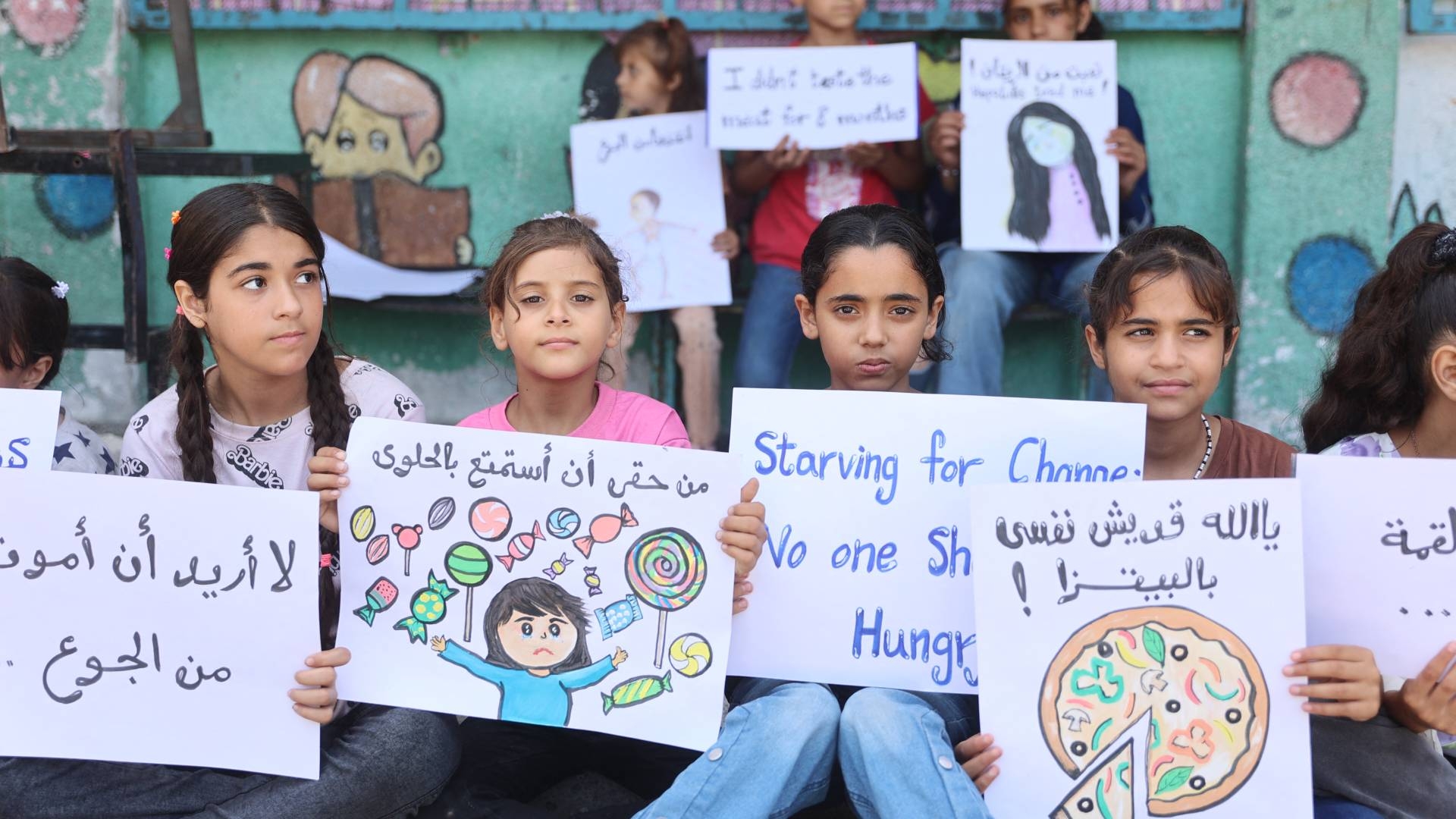Palestinian children hold signs at a UN school housing displaced Palestinians in Gaza City on 4 June 2024, amid the ongoing Israeli war on Gaza.