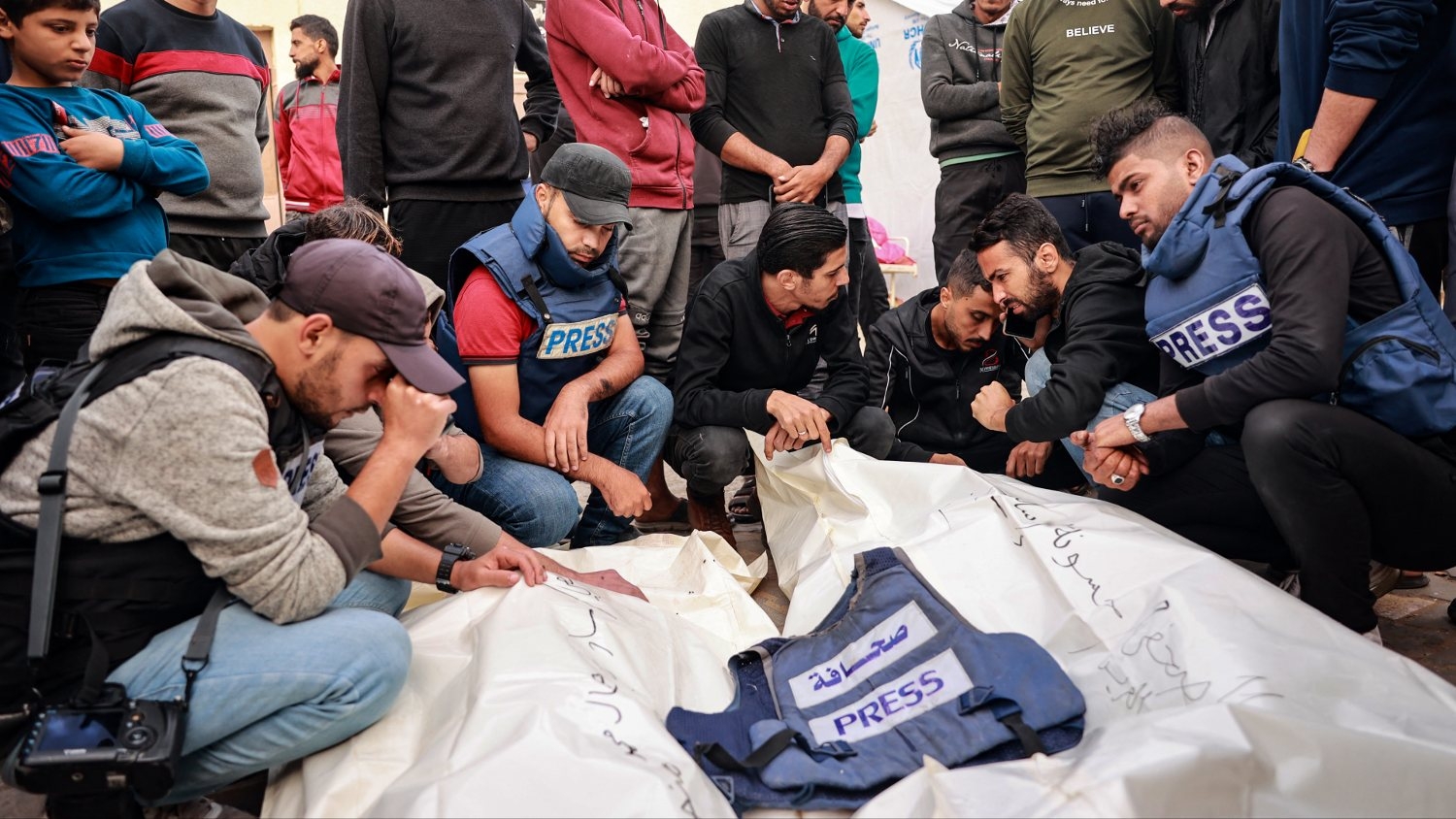 Friends and colleagues of two Palestinian journalists Hasouna Slim and Sari Mansoor, killed in an Israeli strike, mourn over their bodies during their funeral in Deir al-Balah in the southern Gaza Strip on 19 November 2023.