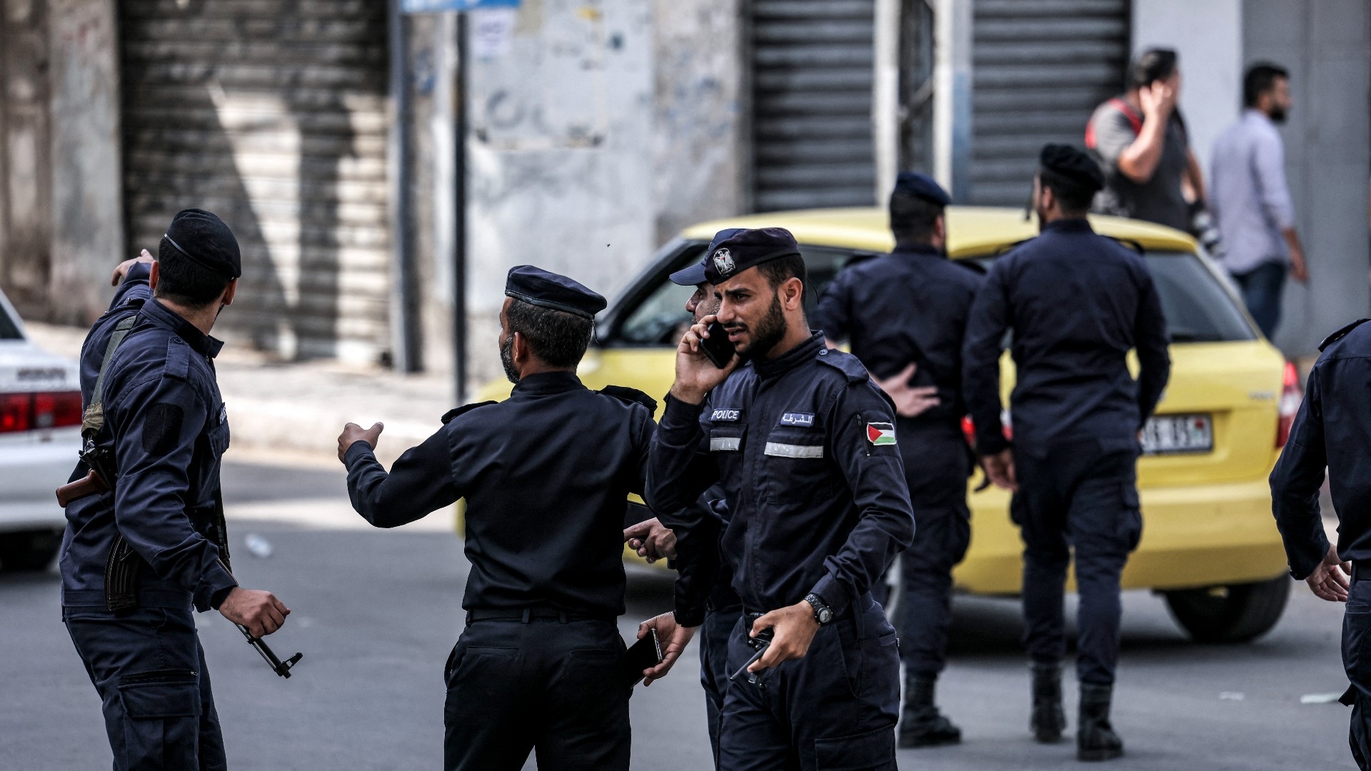 Palestinian policemen stand before closed shops during a general strike in Gaza City on 25 October 2022 (AFP/File photo)