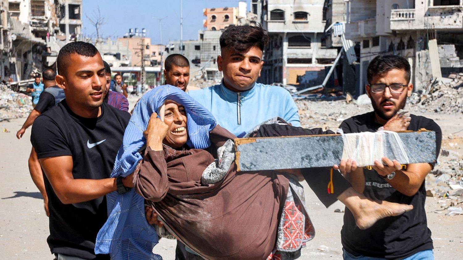 Men carry an injured woman in the Jabalia camp for Palestinian refugees on 9 October 2024 after Israel called for the forced displacement of Palestinians residing in the northern Gaza Strip.