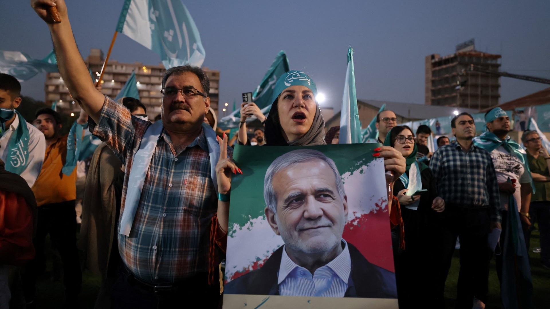 A woman holds a picture of Iranian reformist candidate Masoud Pezeshkian during a campaign rally in Tehran on 3 July 2024 (AFP/Atta Kenare)