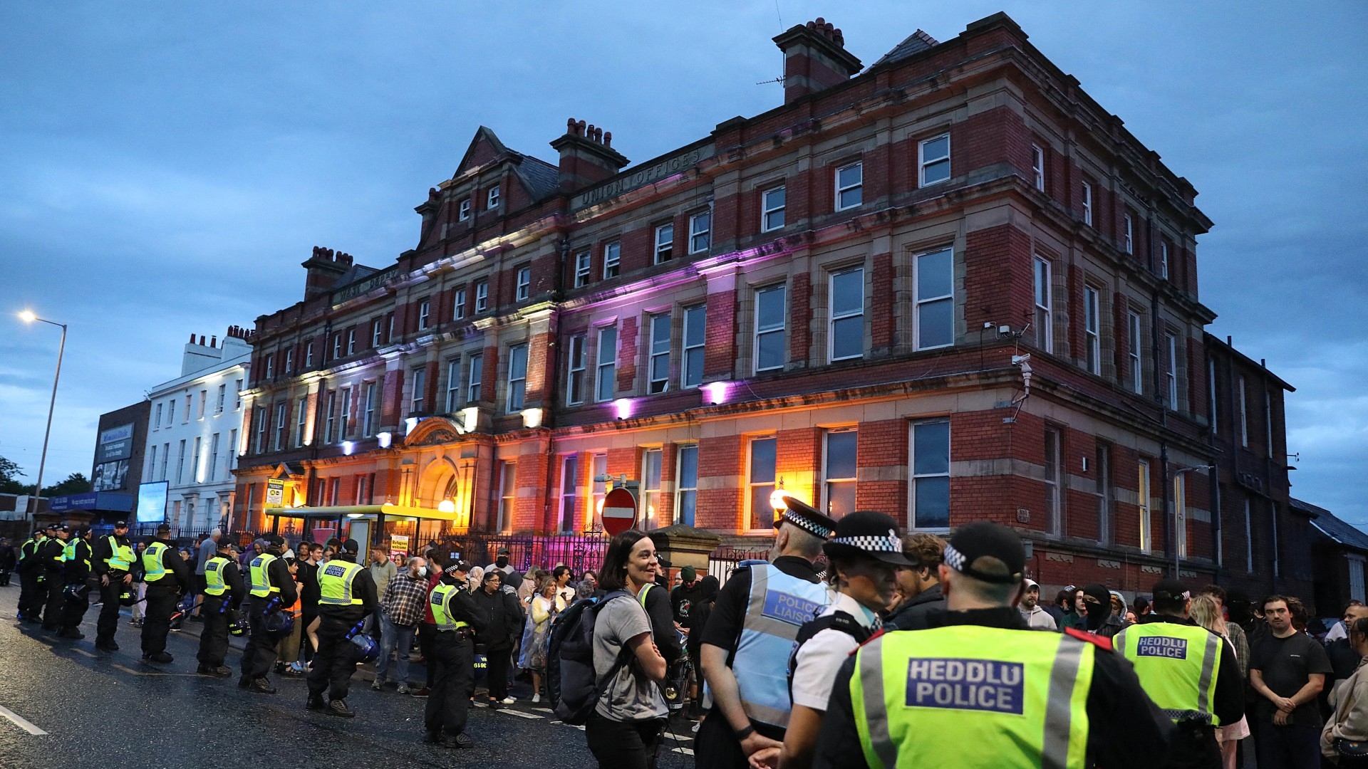 Police officers and locals stand guard outside the Abdullah Quilliam Mosque in Liverpool on 2 August 2024 (AFP/Ian Cooper)