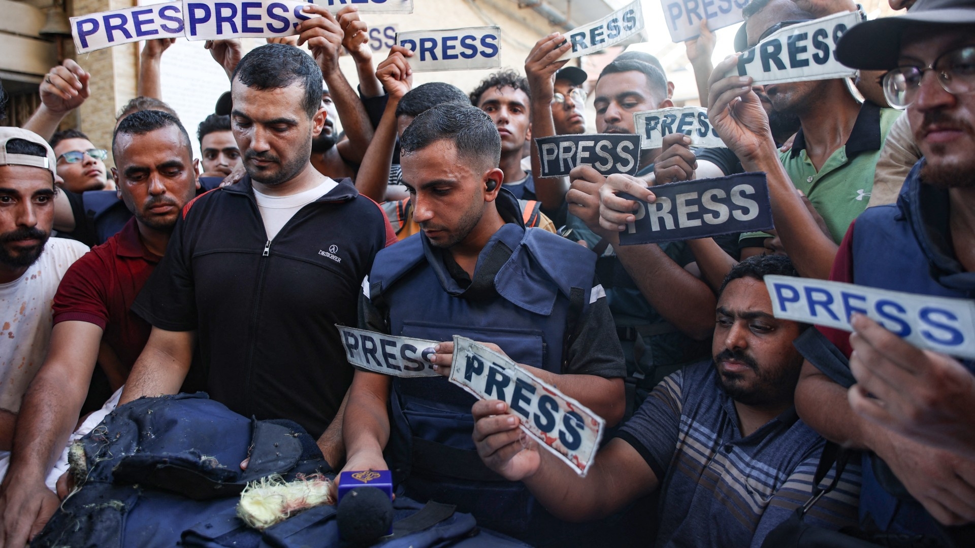 Mourners and colleagues holding 'press' signs surround the body of Al-Jazeera Arabic journalist Ismail al-Ghoul, killed along with his cameraman Rami al-Refee in an Israeli strike on 31 July 2024 (AFP/Omar al-Qattaa)