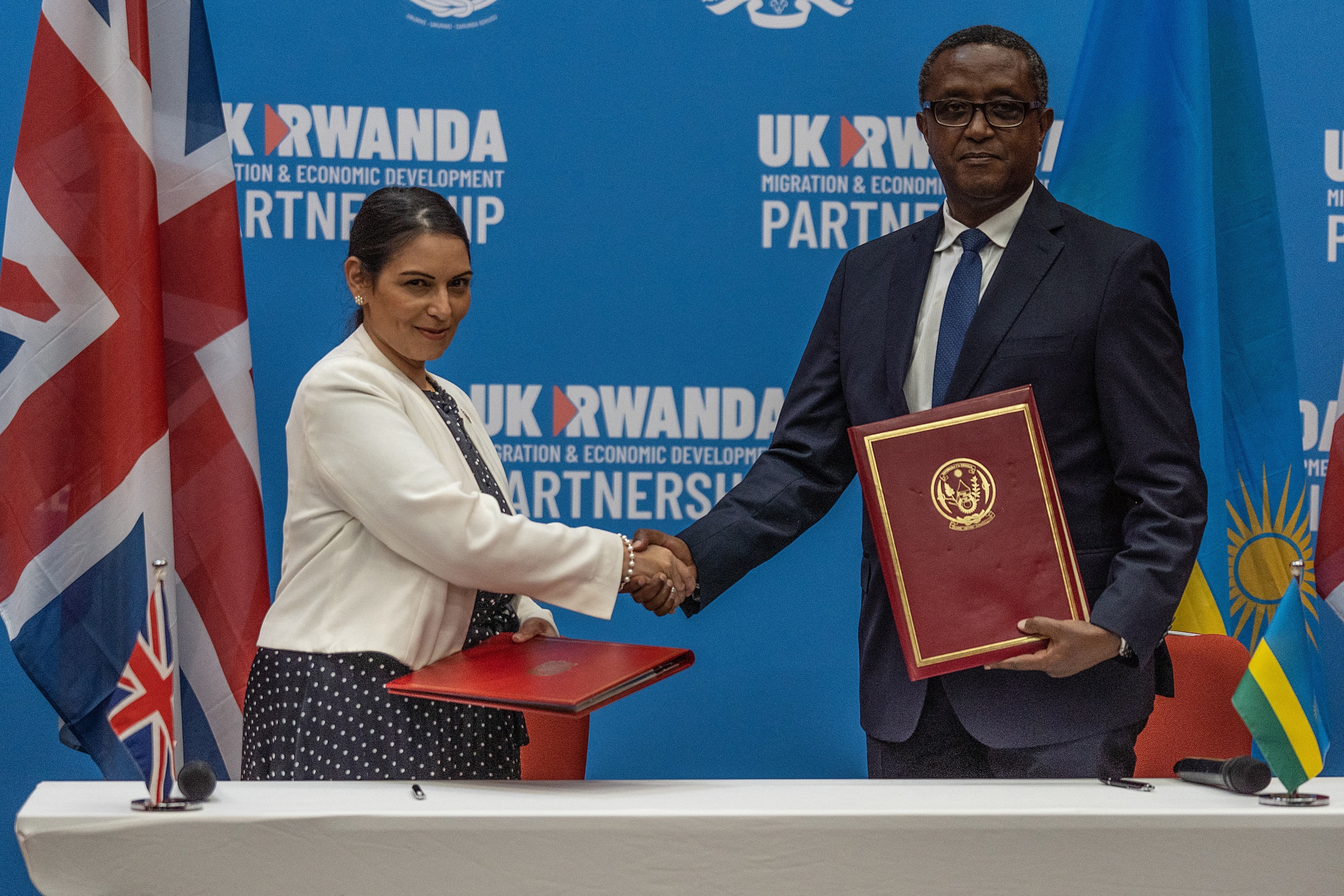 British Home Secretary Priti Patel and Rwandan Minister of Foreign Affairs and International Cooperation Vincent Biruta shake hands after signing an agreement in Kigali, Rwanda on 14 April 2022 (AFP)