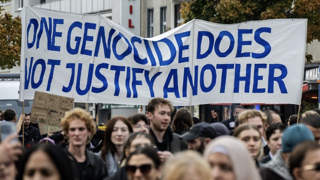 Demonstrators display a banner reading 'One genocide does not justify another' during a pro-Palestinian rally in Berlin on 19 October 2024 (John MacDougall/AFP)