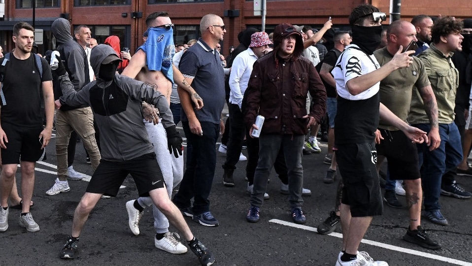 A masked protester throws a can of beer towards riot police in Bristol, southern England, on 3 August 2024 during an 'Enough is Enough' demonstration (Justin Tallis/AFP)