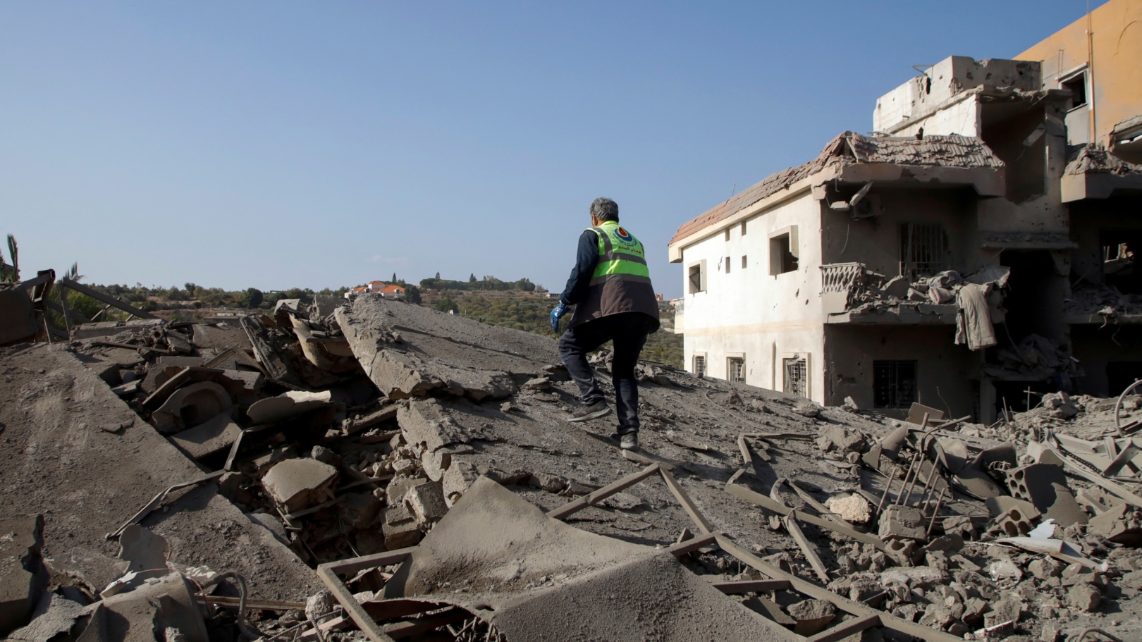 A civil defence member of the Islamic Health Authority walks on rubble at a site damaged by an Israeli strike in Qana, south Lebanon on 16 October 2024 (Reuters/Stringer)