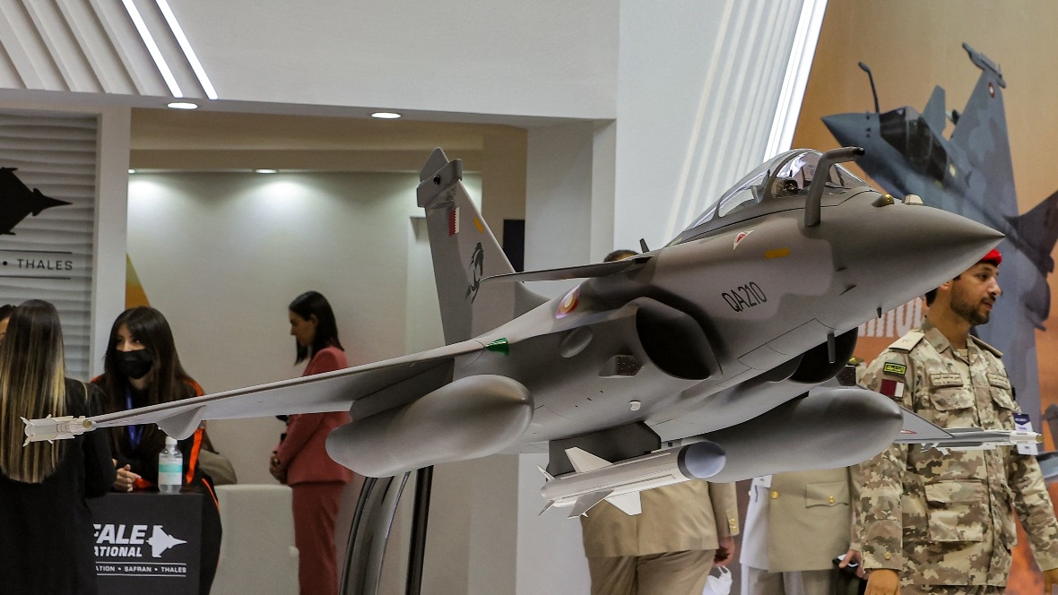 Attendees stand by a model of a Qatar Emiri Air Force French-made Rafale fighter jet during the Doha International Maritime Defence Exhibition in Qatar's capital Doha on 21 March 2022.