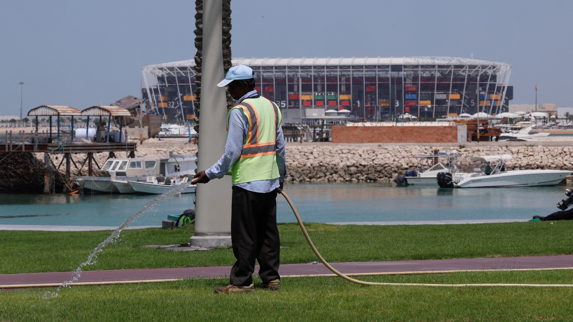 A worker waters the grass near Stadium 974 in Doha, Qatar on 10 May 2023 (AFP)