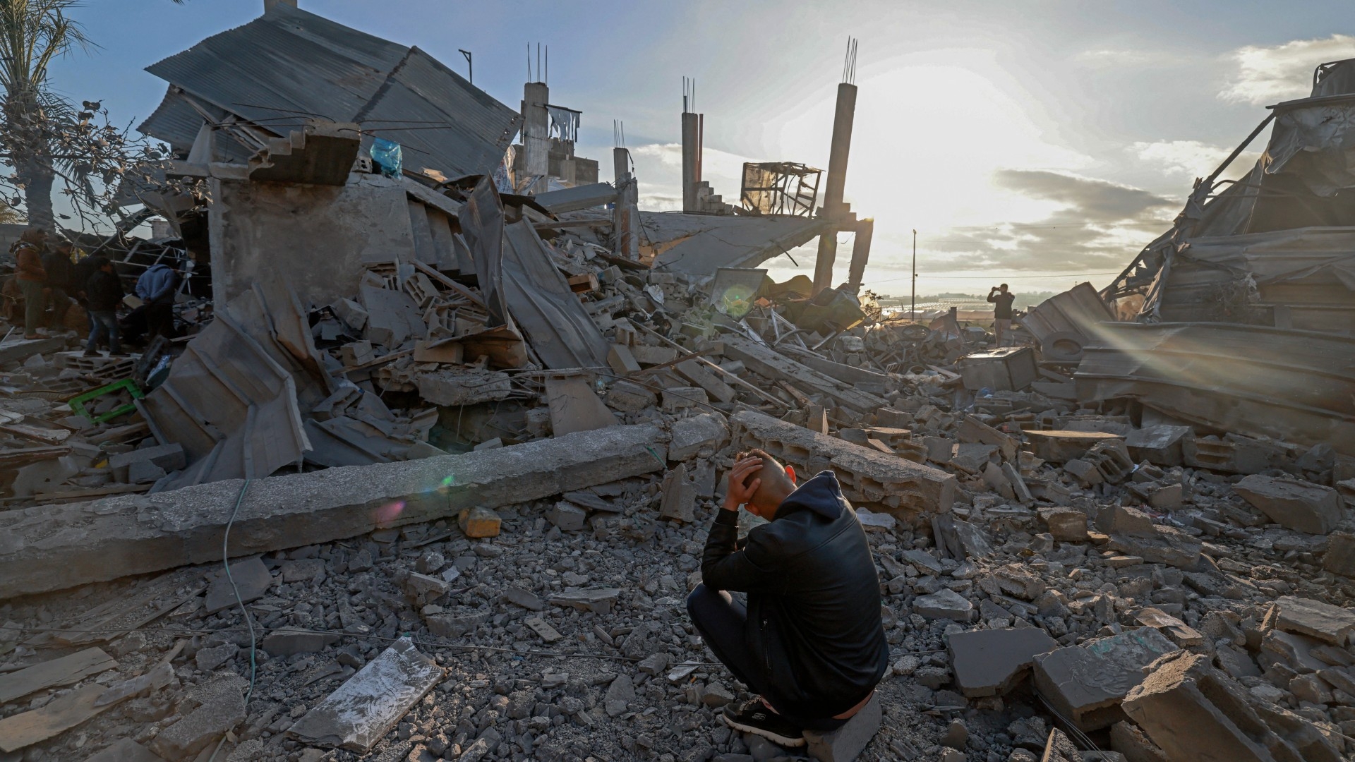 A man sits amid the debris of destroyed houses in the aftermath of Israeli bombardment in Rafah in the southern Gaza Strip on 22 February 2024 (AFP/Mohammed Abed)
