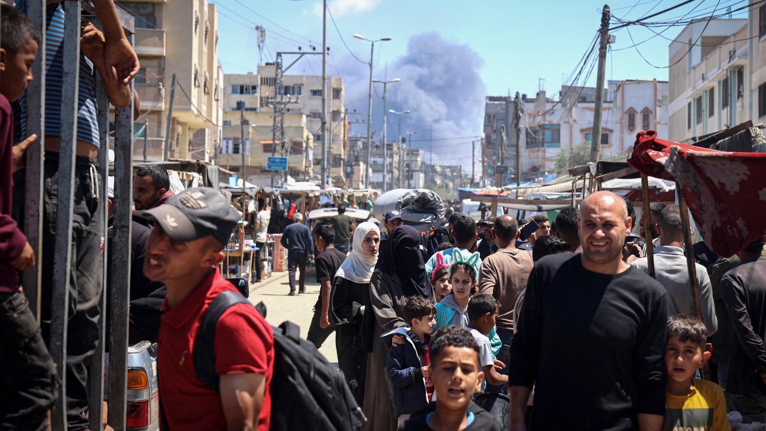 Palestinians crowd a street as smoke billows nearby from Israeli strikes in Rafah in the southern Gaza Strip on 7 May 2024.