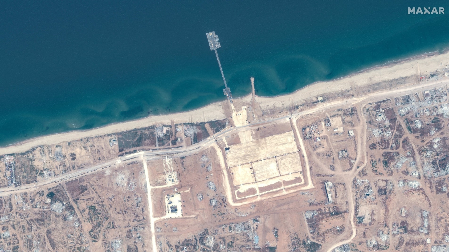 A satellite image shows the floating pier and approaching aid trucks on the Gaza shoreline on 18 May 2024 (Maxar Technologies/Handout via Reuters)