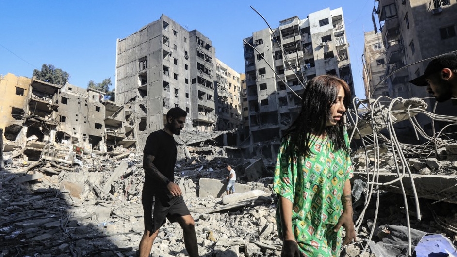 People walk in the rubble of buildings in Beirut levelled on 27 September by Israeli strikes that killed Hezbollah leader Hassan Nasrallah, 29 September 2024 (AFP)