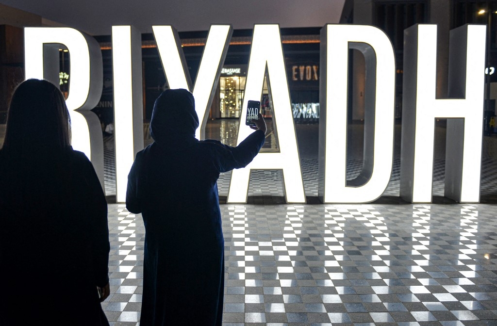A woman uses her phone to take a picture of a lit "I LOVE RIYADH" sign at a shopping centre in Saudi Arabia's capital Riyadh on 31 October 2020 (AFP)