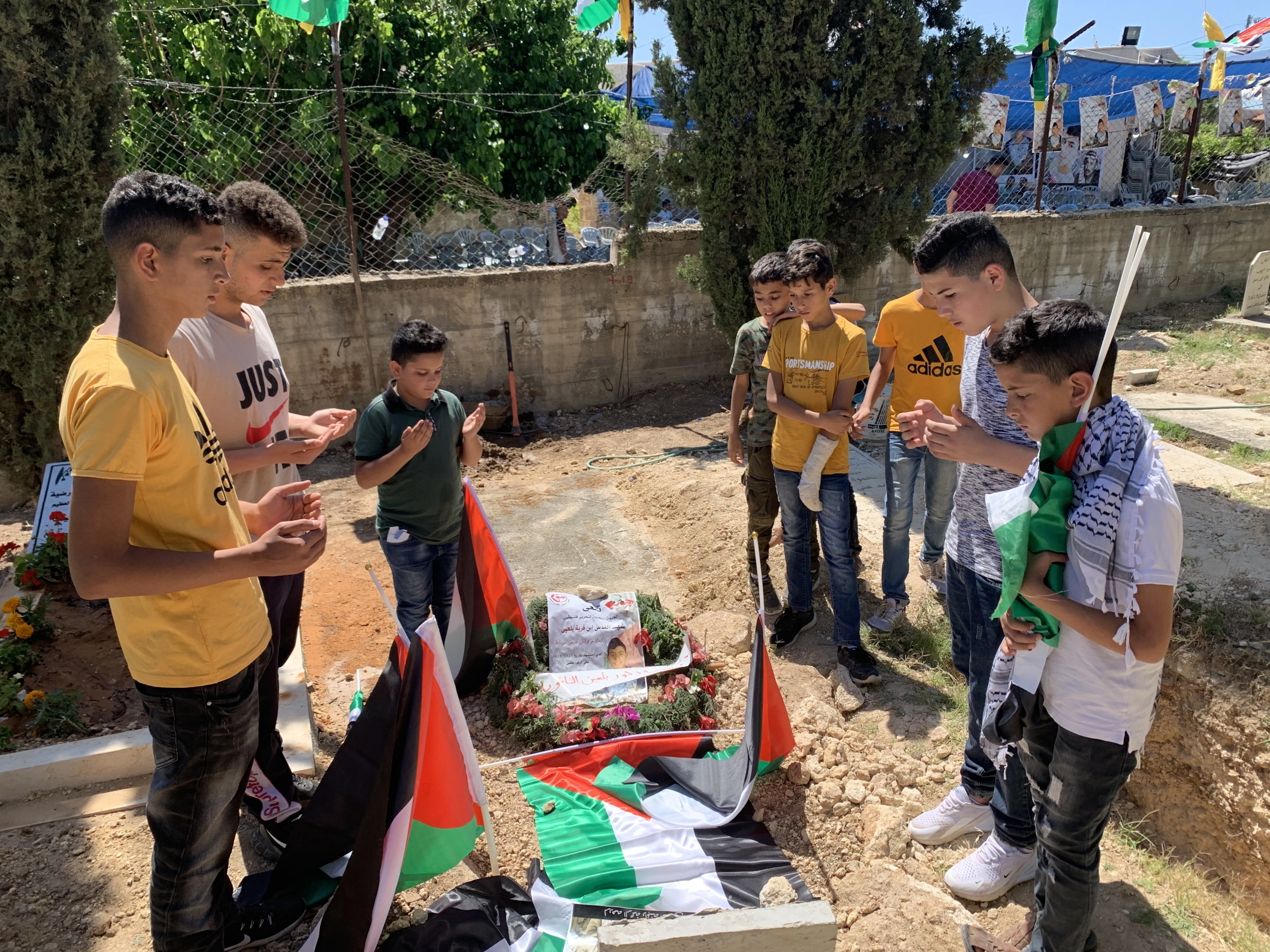 Friends of Islam Burnat recite a prayer for him at his grave. Burnat was shot dead by Israeli forces.