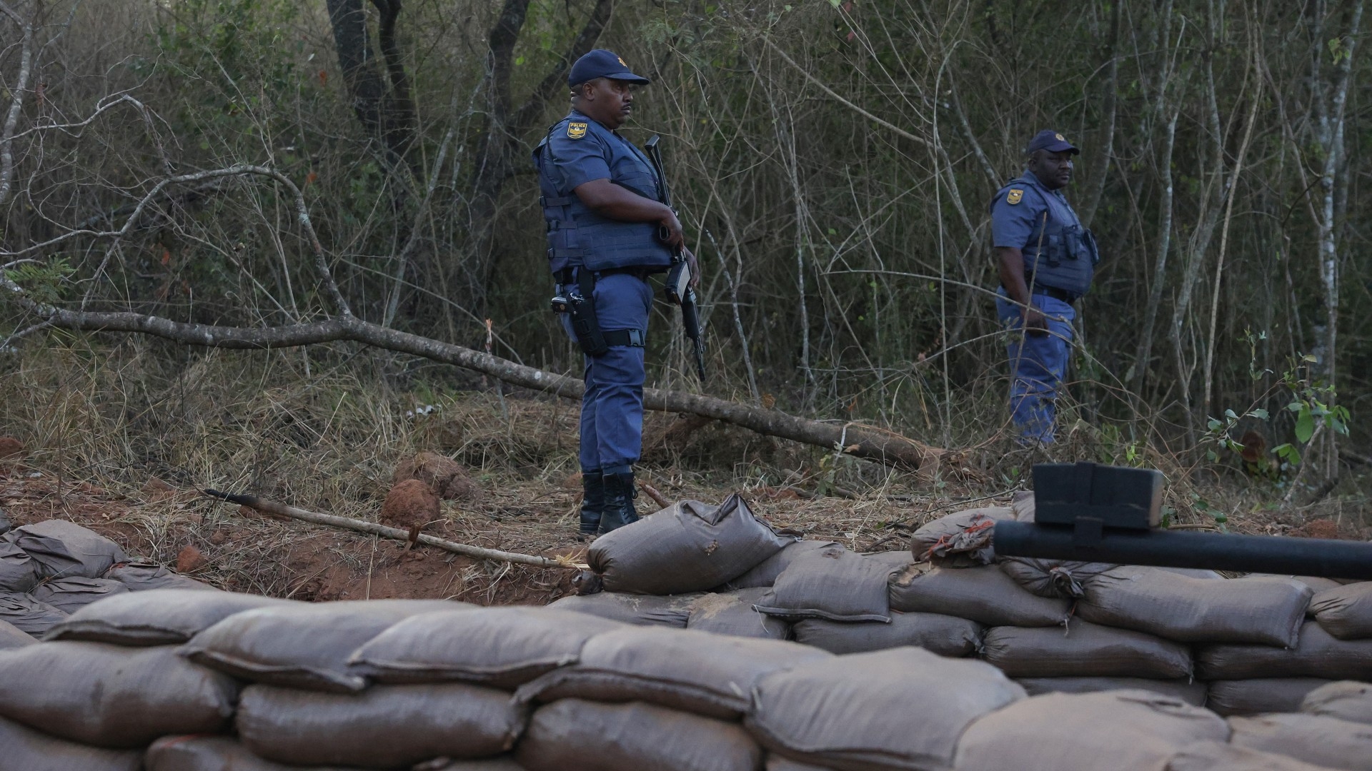 South African Police Services (SAPS) officers stand at a farm where they detained ninety five Libyan nationals in White River, Mpumalanga province on 27 July 2024 (AFP/Phill Magakoe)