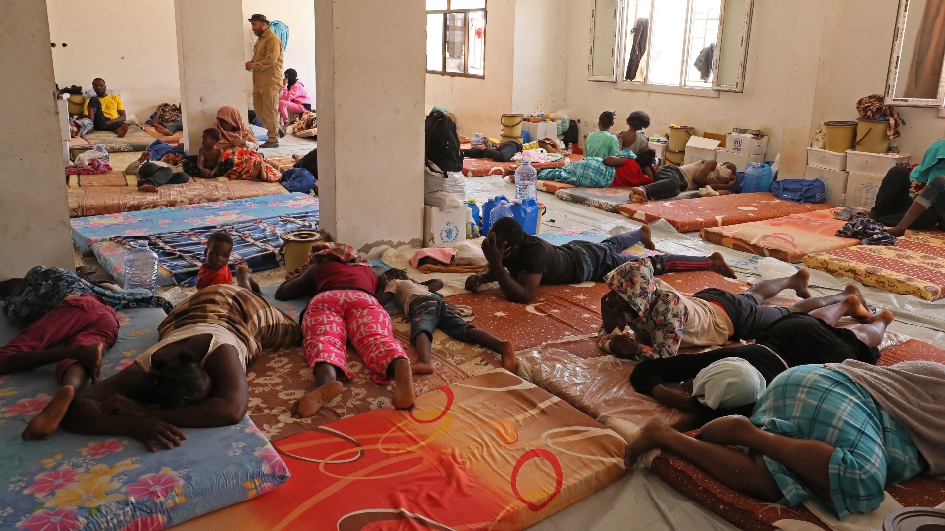 Sub-Saharan Africans expelled from Tunisia rest at a shelter after being rescued by Libyan border guards near the border town of Al-Assah on 16 July 2023 (AFP)