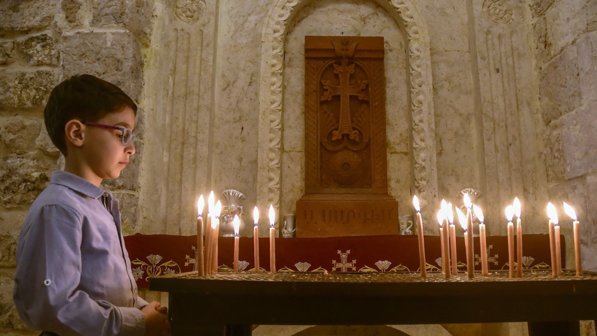 A Syrian Christian boy attends Easter Sunday mass at the Fourty Martyrs Armenian church in the northern city of Aleppo on 17 April 2022 (AFP)