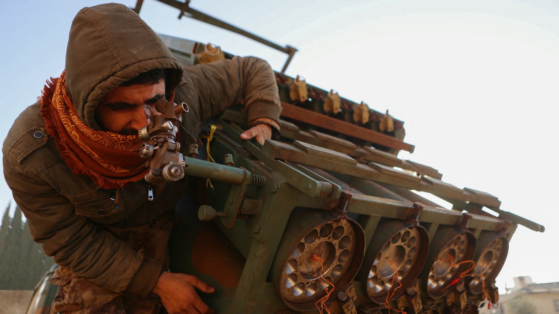 A rebel inspects a seized Syrian army rocket launcher in the Khan al-Assal district of Aleppo on 29 November 2024 (Aaref Watad/AFP)