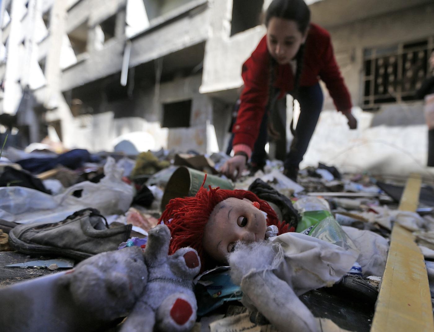 Une jeune fille fouille dans des affaires abandonnées dans les décombres des rues du camp palestinien de Yarmouk, dans la banlieue sud de la capitale syrienne Damas, le 25 novembre 2020 (AFP)