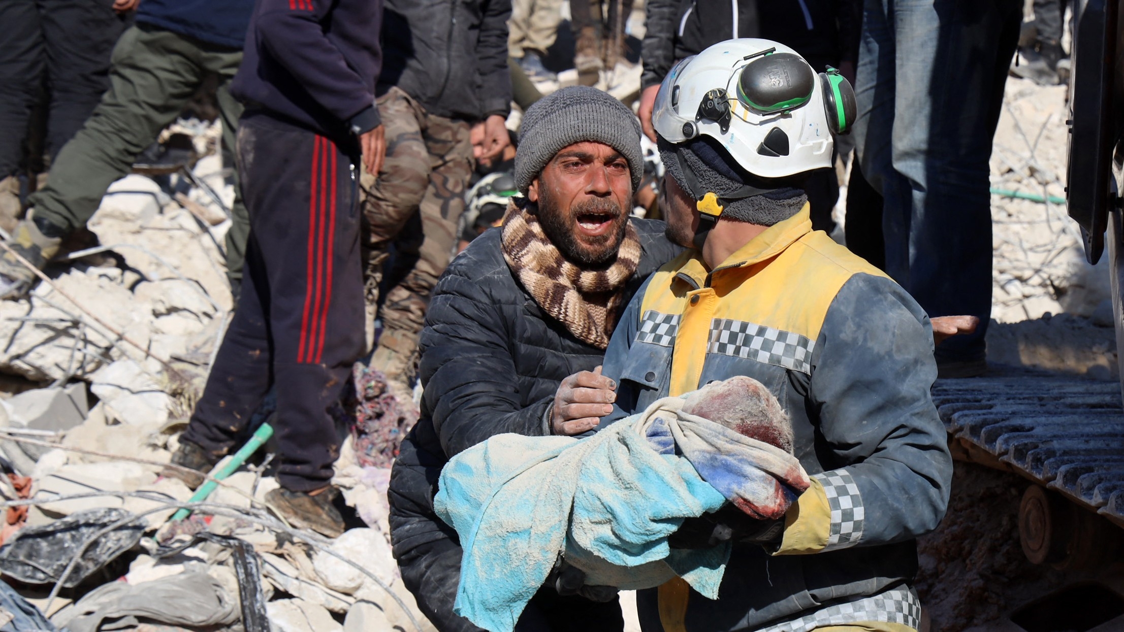 A man reacts as the body of his baby is pulled out from the rubble by a White Helmets rescue worker in Harim, in Syria's northwestern Idlib province, on 8 February 2023.