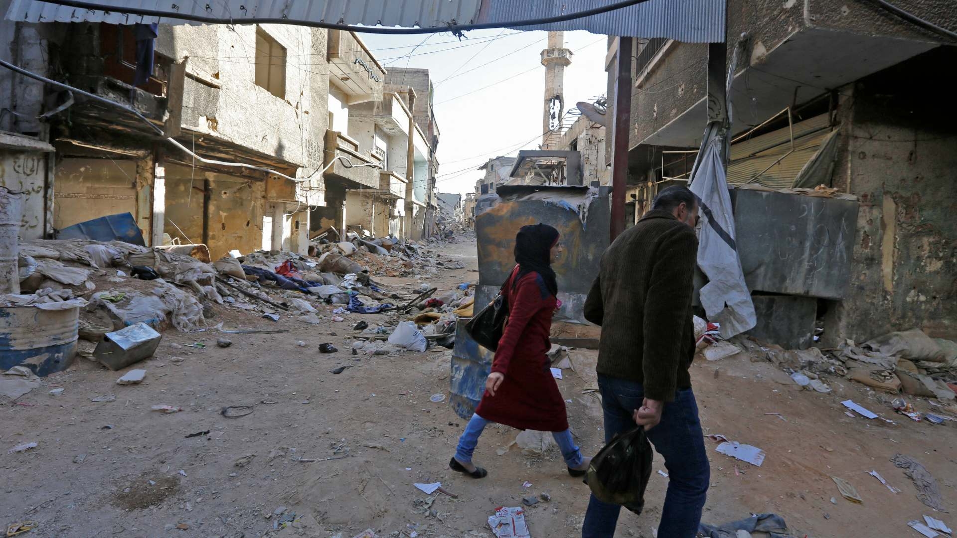 People walk amid rubble of destroyed buildings in a street in Tadamon neighbourhood of Damascus on 3 November 2018.