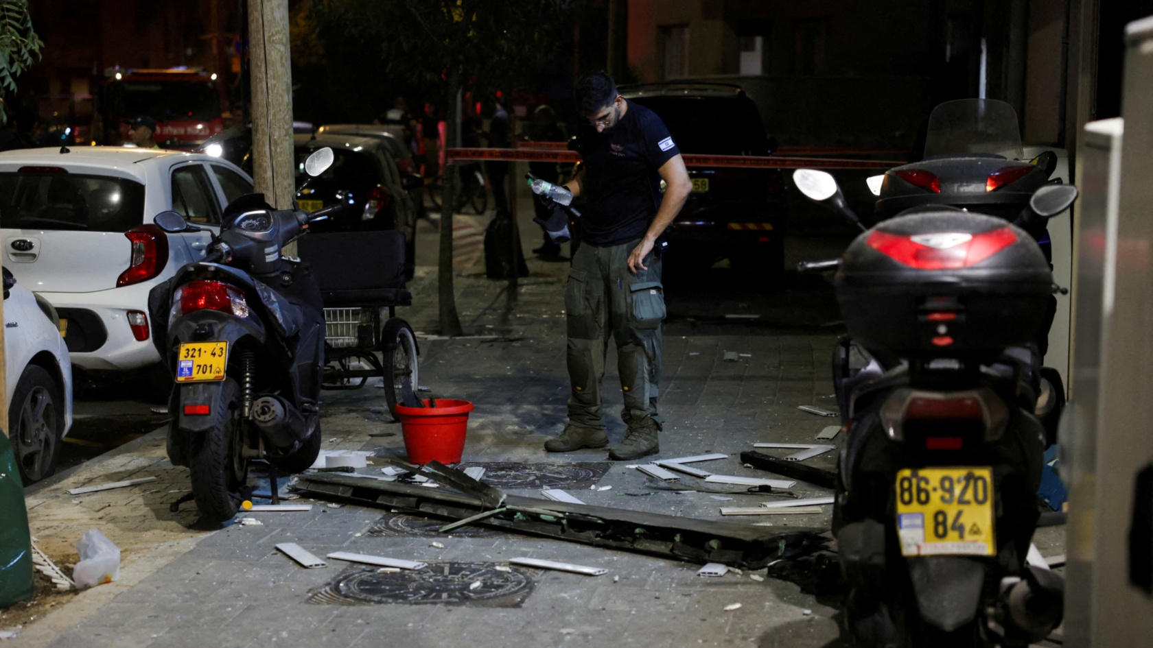 An investigator examines what seems to be a part of the drone that hit Tel Aviv on 19 July 2024 (Ricardo Moares/Reuters)