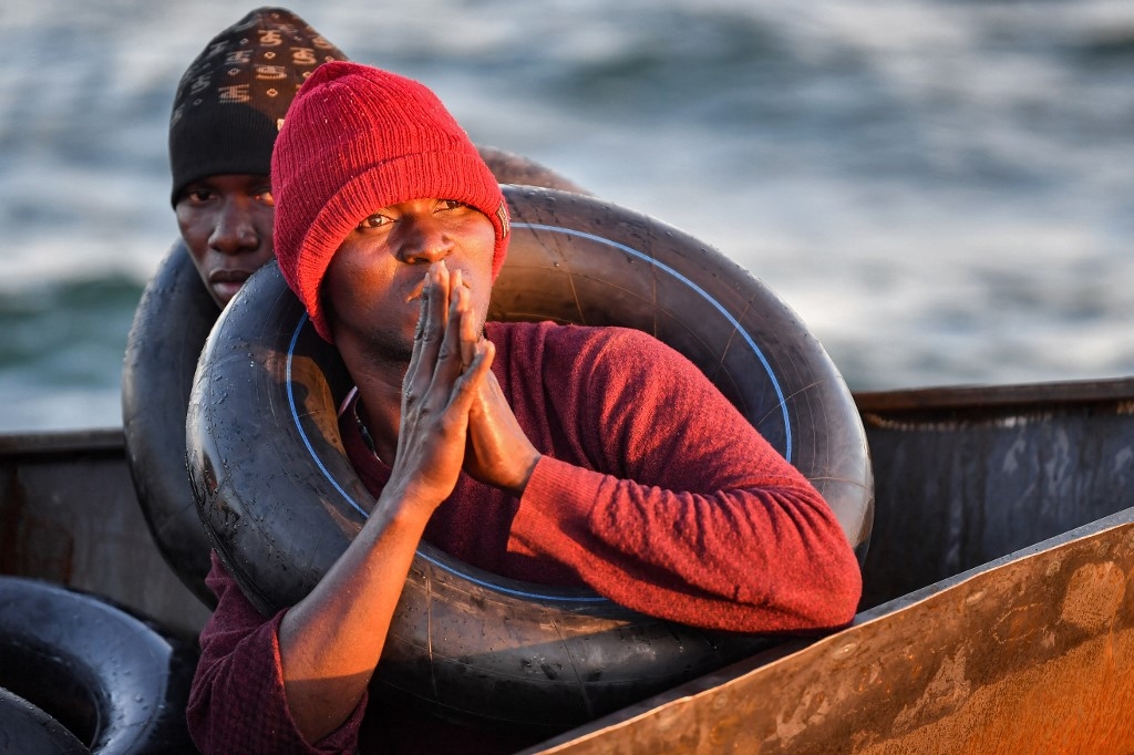 Des migrants d’Afrique subsaharienne sont assis dans un bateau de fortune utilisé pour se diriger clandestinement vers la côte italienne. Ils ont été retrouvés par les autorités tunisiennes au large de Sfax, le 4 octobre 2022 (AFP/Fethi Belaïd)